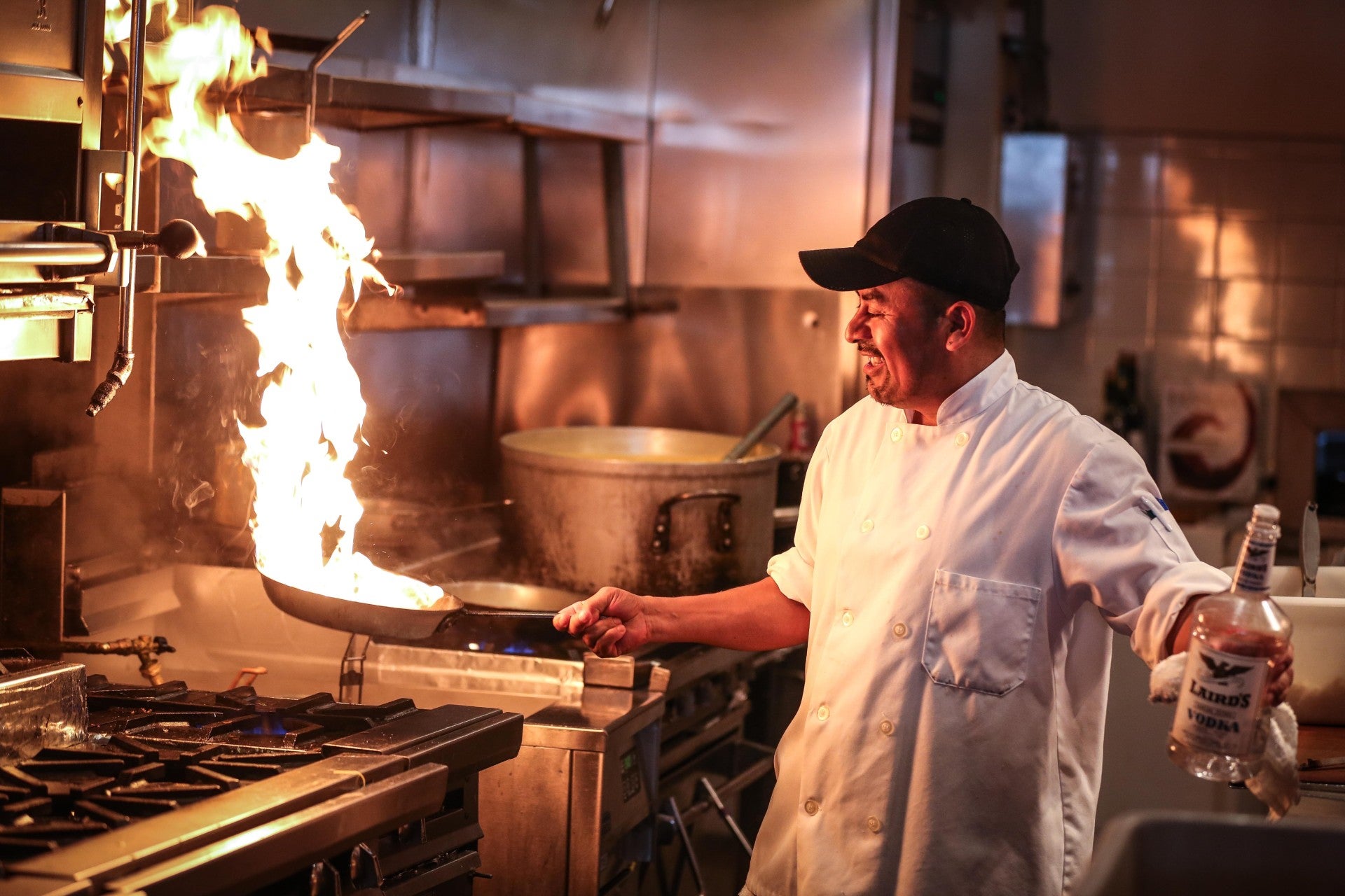 A chef cooking with a flaming pan.