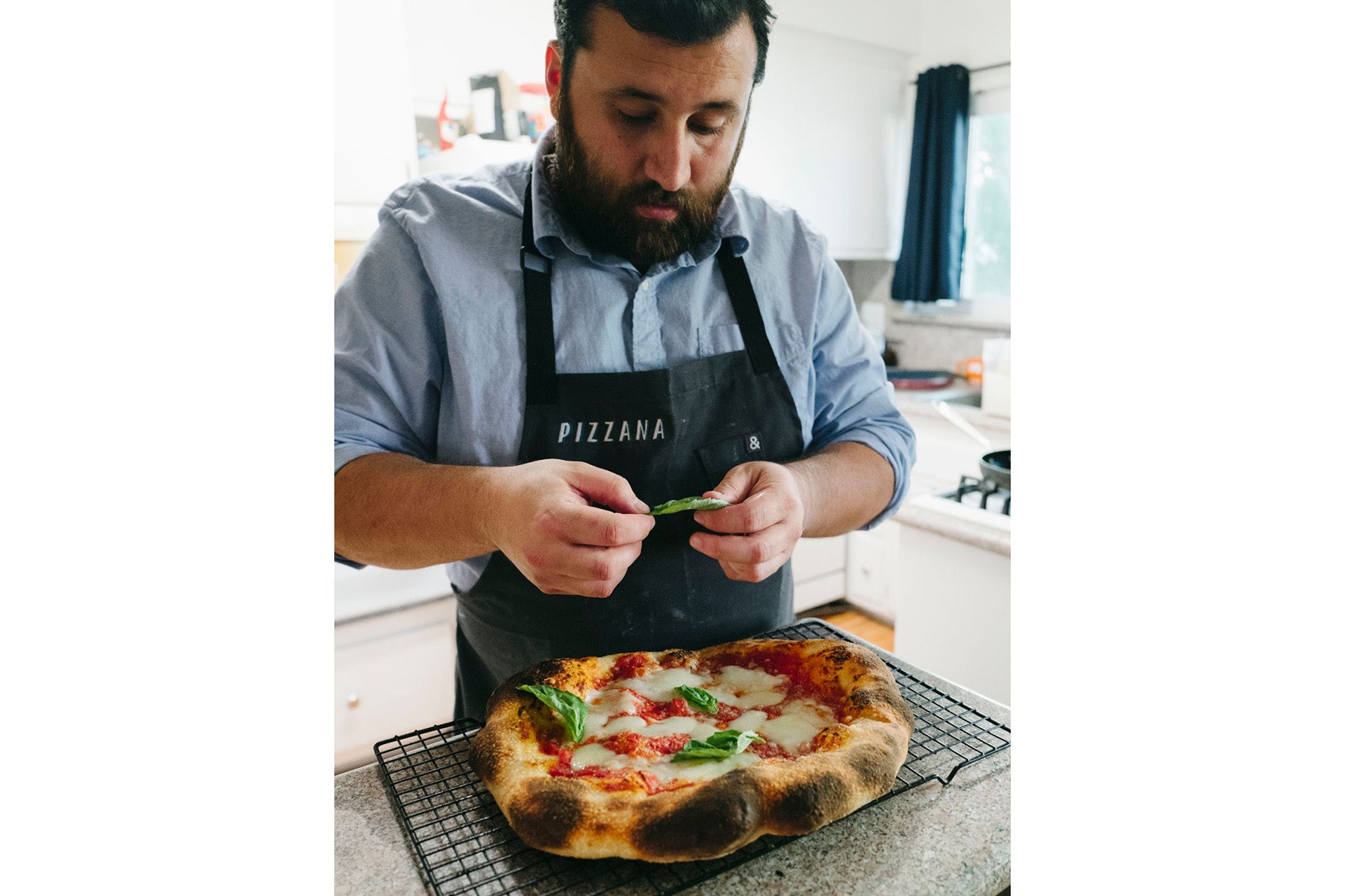 Daniele Uditi decorating a pizza with basil