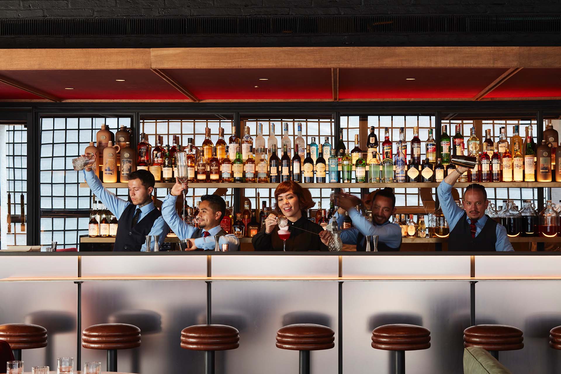 Laura Espinosa with her team playing with cocktails behind the bar