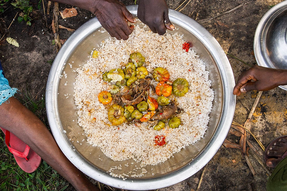 overhead-shot-of-large-bowl-of-food-outdoors-on-ground-with-hands