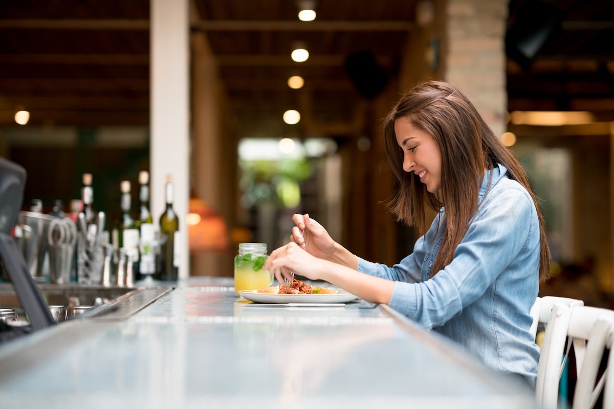 Girl sitting at restaurant bar and enjoying meal