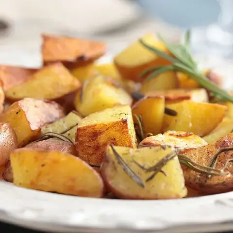 A bowl of roast potatoes with rosemary.