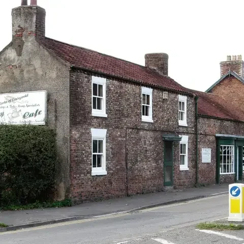 Red brick bakery and café with white windows on a quiet street, serving local treats in a rustic, welcoming setting