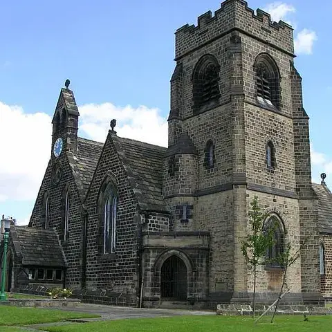 St John’s Church, a beautiful stone structure with a clock tower,surrounded by a manicured green lawn under a bright blue sky