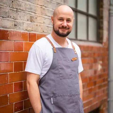Chef Tom Cenci standing against a wall.
