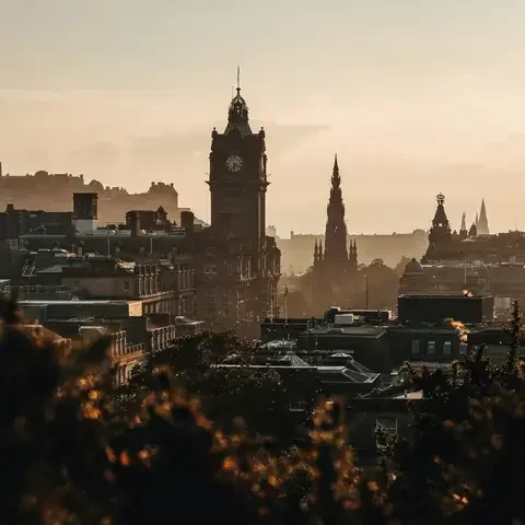 Edinburgh skyline at sunset, with the Balmoral clock tower, Scott Monument and the city’s medieval charm in warm golden light