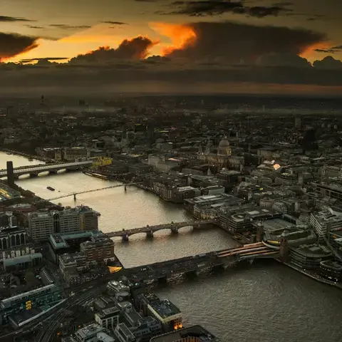 London skyline at sunset with Thames, bridges, St. Paul’s Cathedral, and dramatic clouds glowing in the evening light