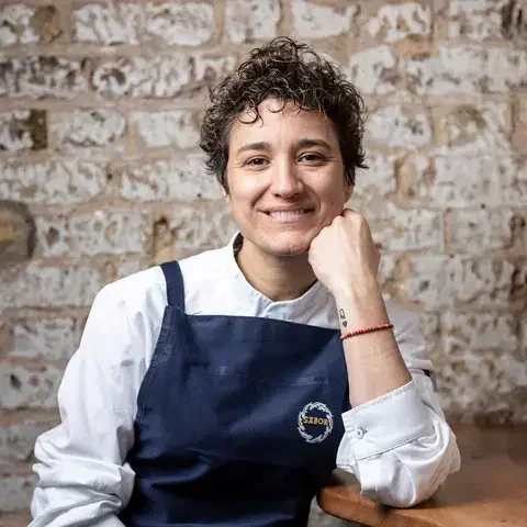 Chef Nieves Barragán Mohacho in front of a raw brick wall.