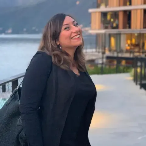 Journalist Mariarosaria Bruno smiling next to a body of water.