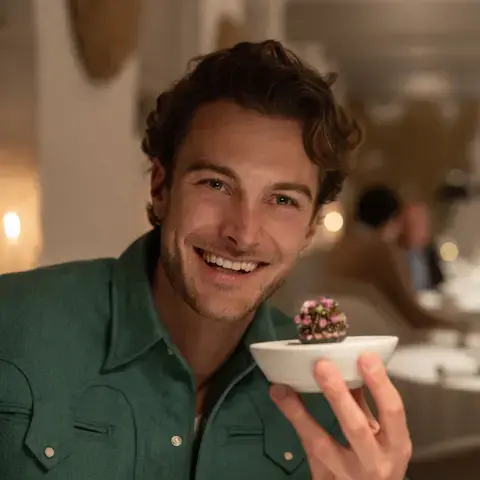 Jesse Burgess holding an elegant dish in a restaurant.