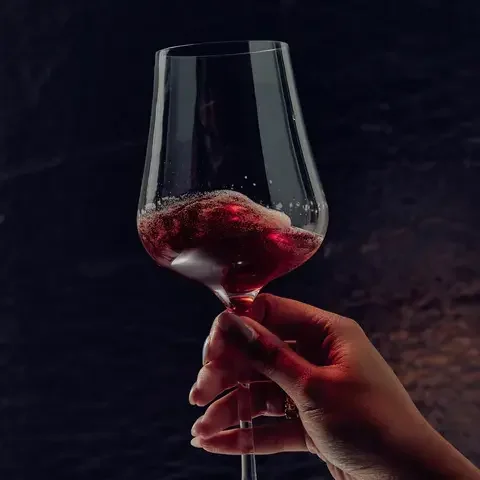 A woman's hand holding a wine glass of red Non, non-alcoholic beverage.