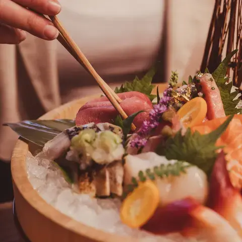 A woman eating sashimi with chopsticks at Yamato.
