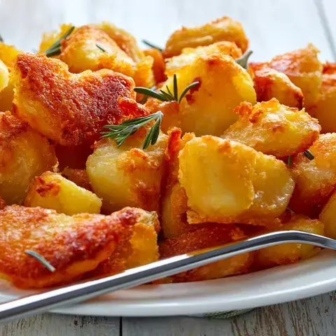 Crispy roast potatoes on a plate with a fork.