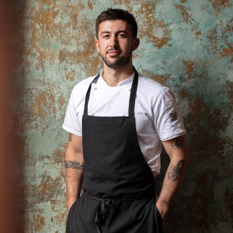 Chef Filippo Alessandri in front of a textured wall.