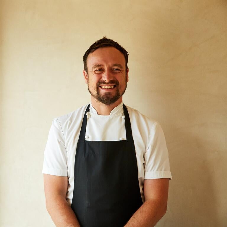 Chef Sam Carter in an apron, smiling.