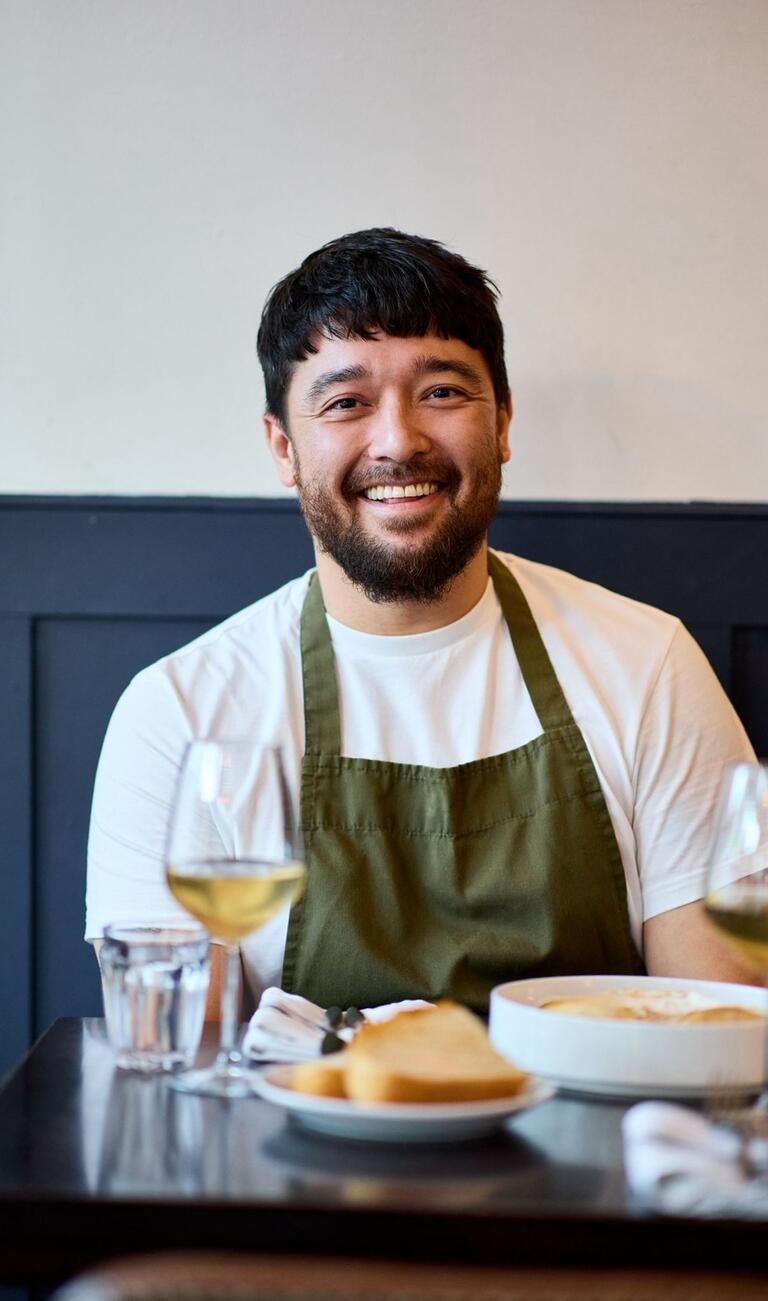 Chef Matty Grove smiling at a restaurant table.