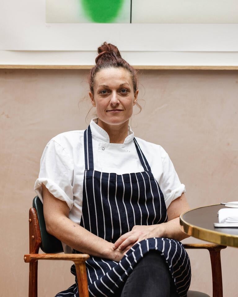 Chef Tarryn Bingle, seated, in an apron and chef whites.