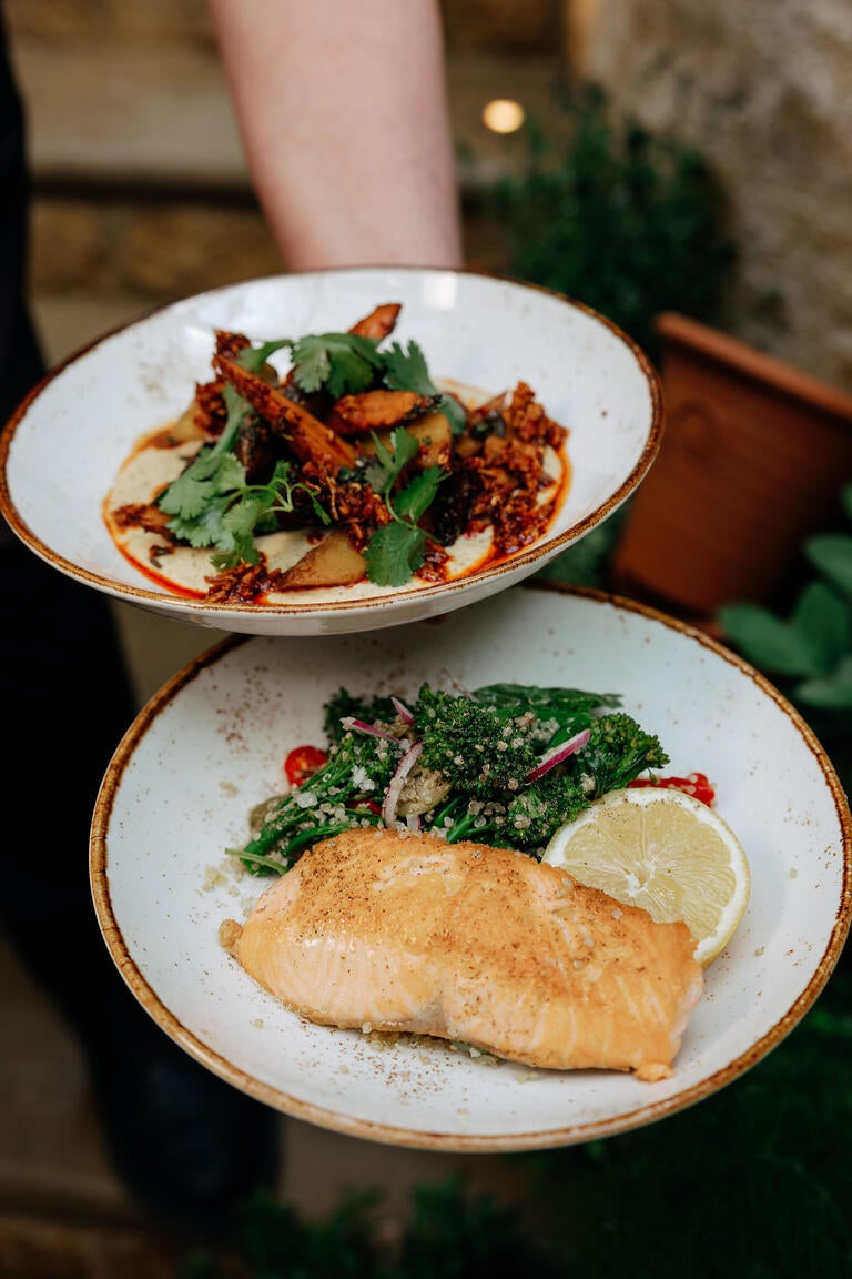 A person holding plates of food at Eleven Bibury in the Cotswolds.