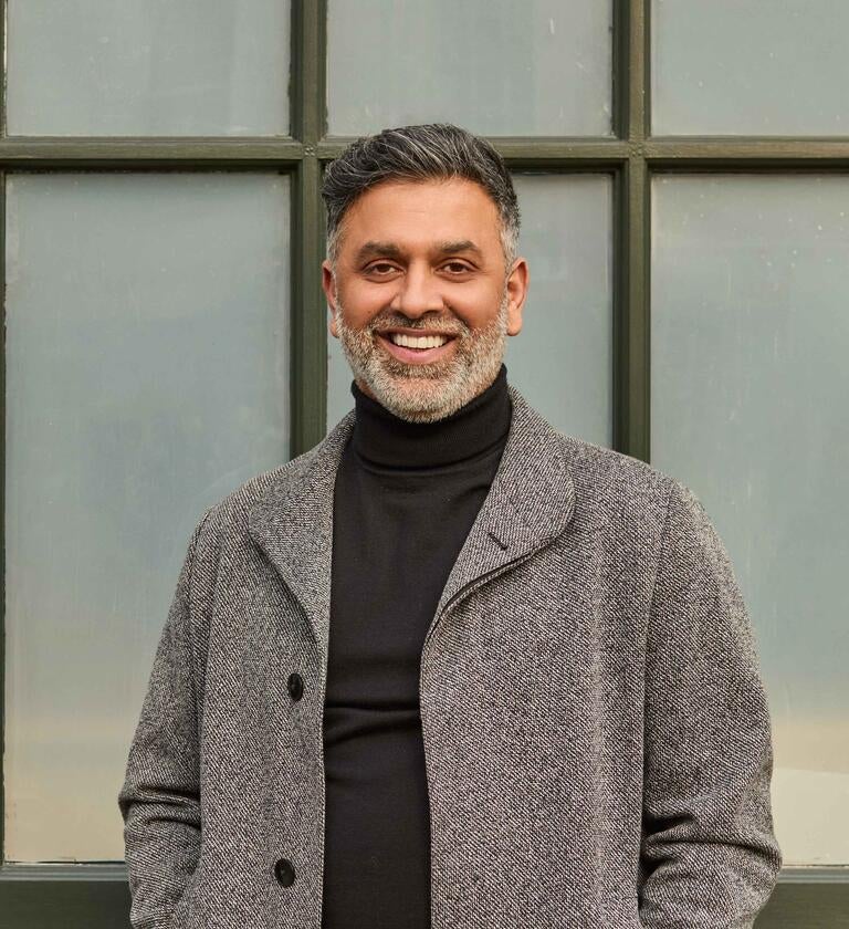 Chef Aktar Islam in a coat smiling.