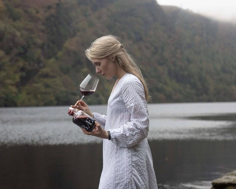 Majken Bech-Bailey sniffing a glass of Baek next to water.