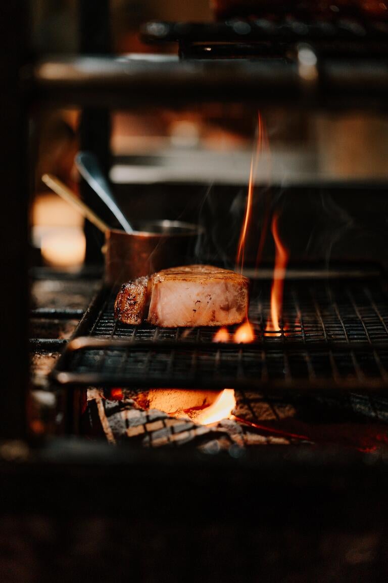 Meat on the grill at Pine, licked by flame.