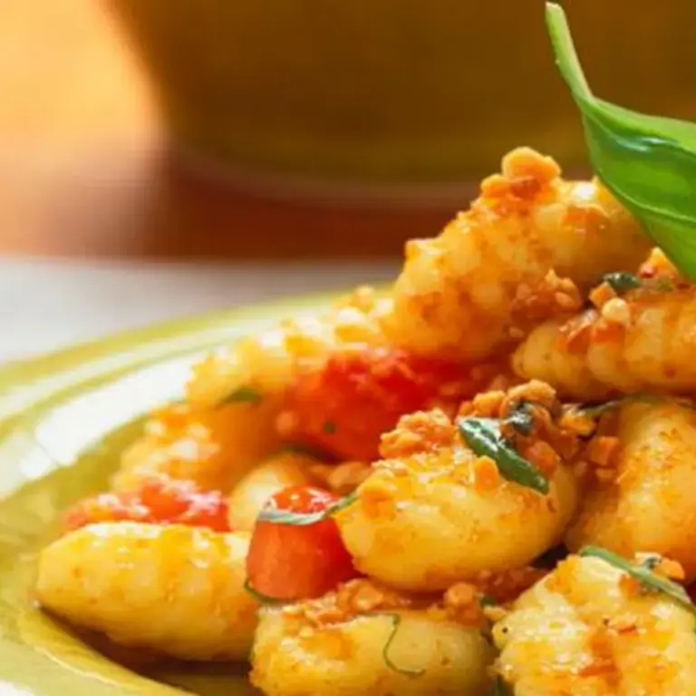 A heaped pile of gnocchi topped with a basil leaf.