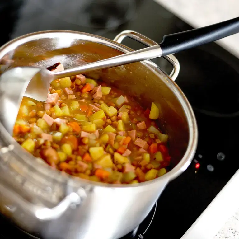 Minestrone soup in a pot with a ladle.