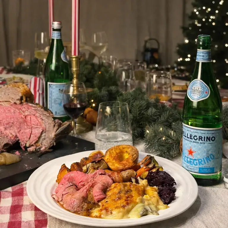 A roast beef dinner on a table with bottles of S.Pellegrino.