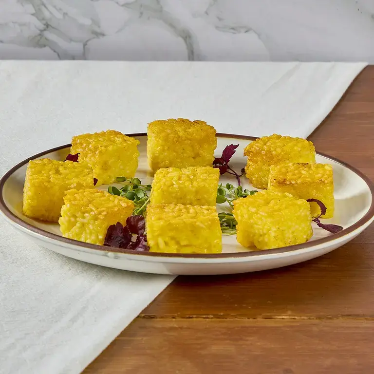 Yellow risotto al sato bites on a plate.