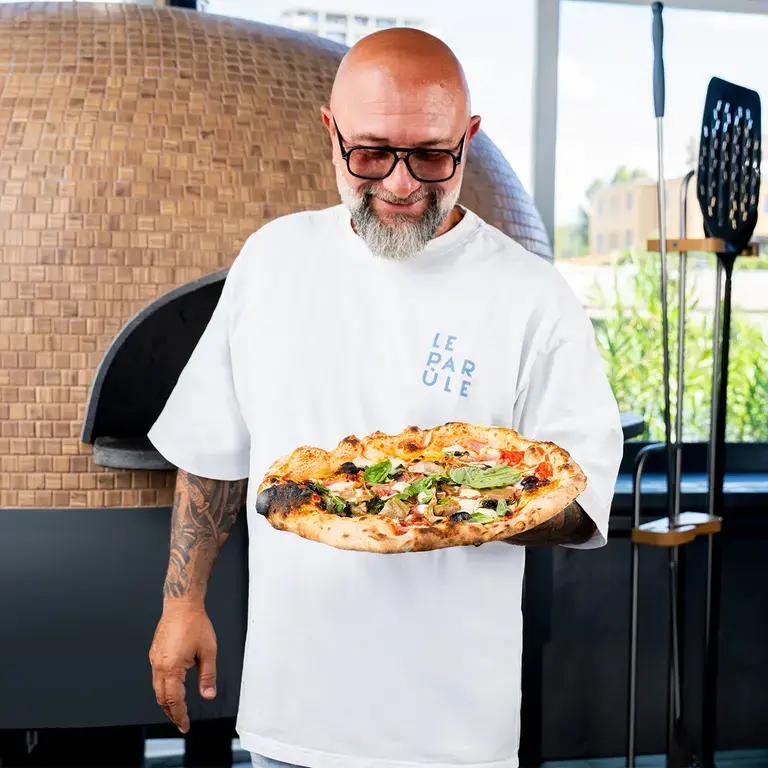Chef Giuseppe Pignalosa holding a capricciosa pizza.