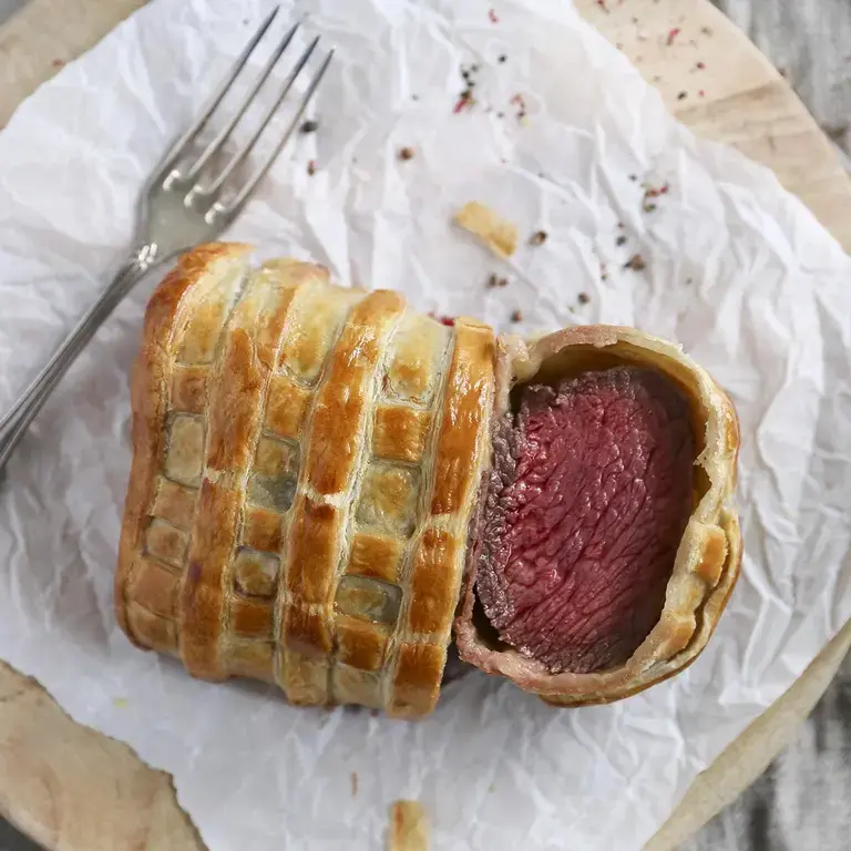 Beef Wellington, sliced on paper.