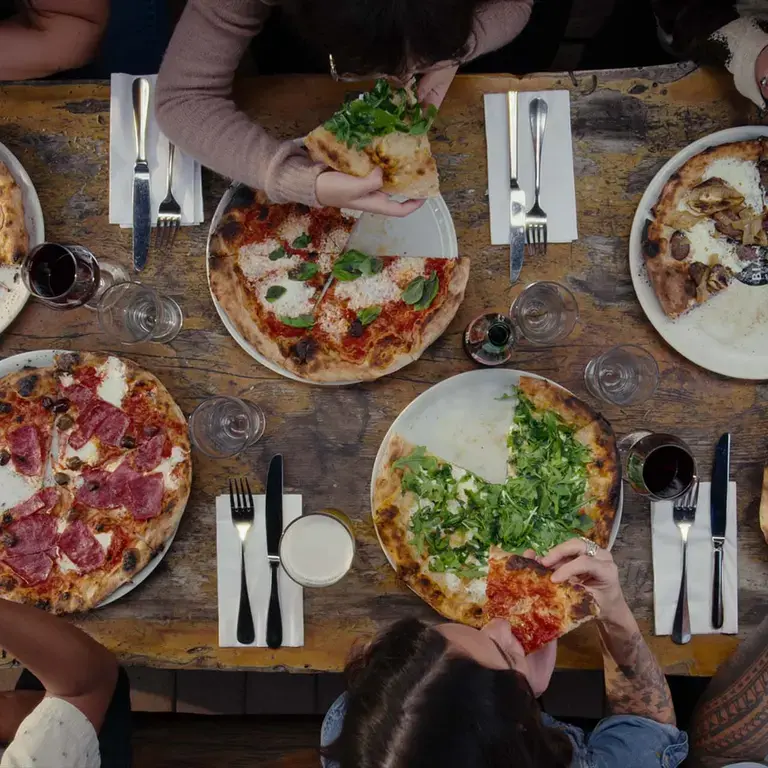 An overhead shot of people eating pizza at a table.