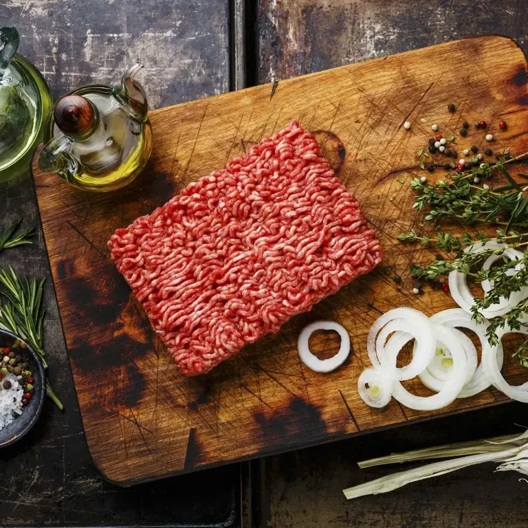 Ground beef and other ingredients on a board.