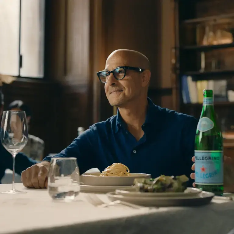 Stanley Tucci at a table with San Pellegrino