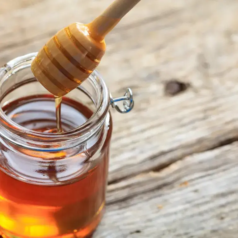 a jar of open honey with a honey dipper