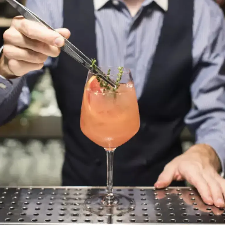 Cointreau spritz, with a barperson adding garnish