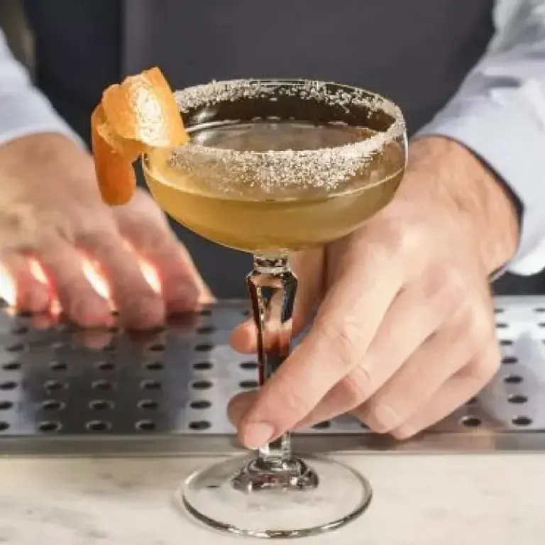 A sidecar cocktail, with a barperson holding the glass.