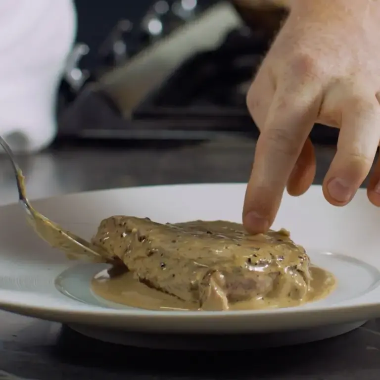 Plating steak with pepper sauce.