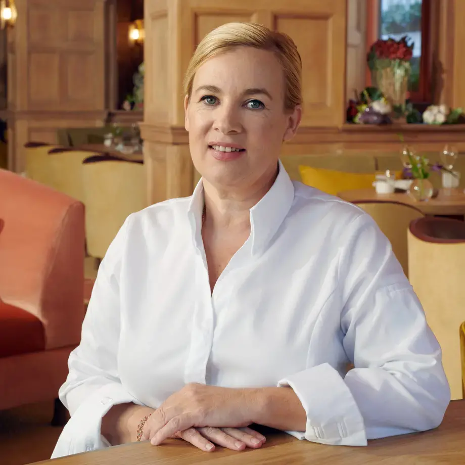Chef Hélène Darroze sitting in a restaurant dining room.