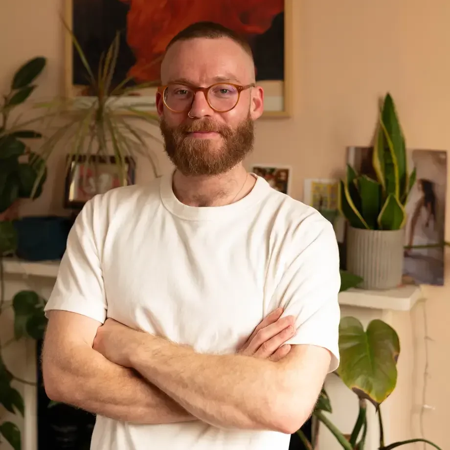 Journalist Lucas Oakeley in a white t-shirt with arms folded.