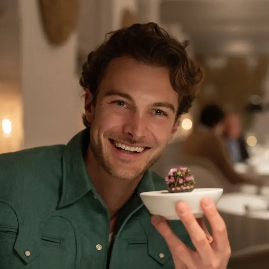 Jesse Burgess holding an elegant dish in a restaurant.