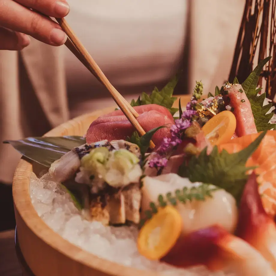A woman eating sashimi with chopsticks at Yamato.