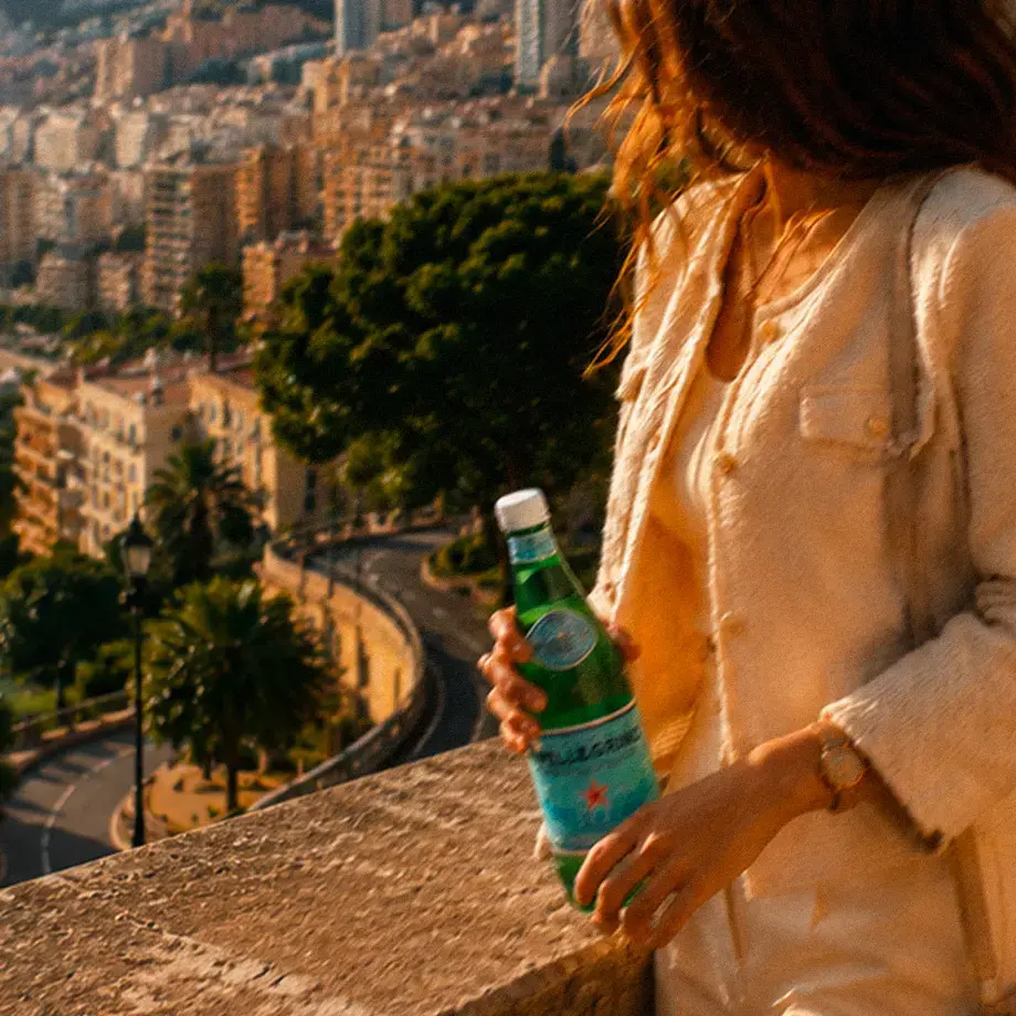 A woman holding a bottle of S.Pellegrino on a balcony in Monte Carlo.