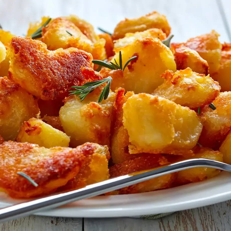Crispy roast potatoes on a plate with a fork.