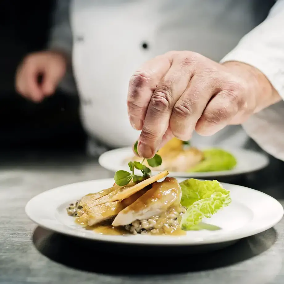 A chef putting the finishing touches to a dish.