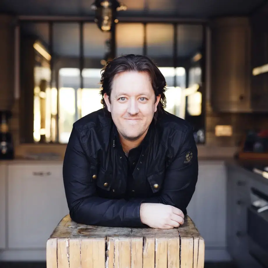 Chef Ashley Palmer-Watts leaning on a butcher's block.