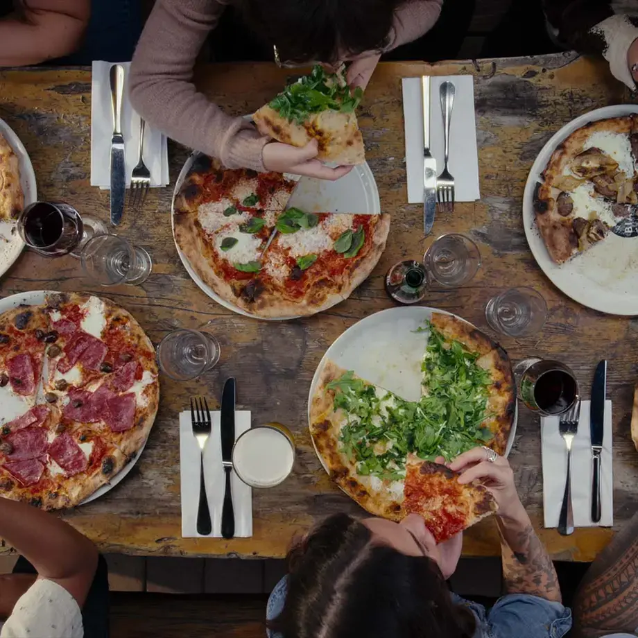 An overhead shot of people eating pizza at a table.