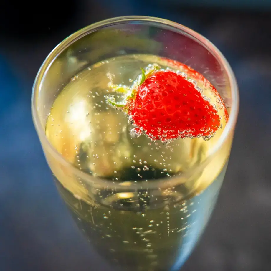A glass of prosecco with a strawberry.