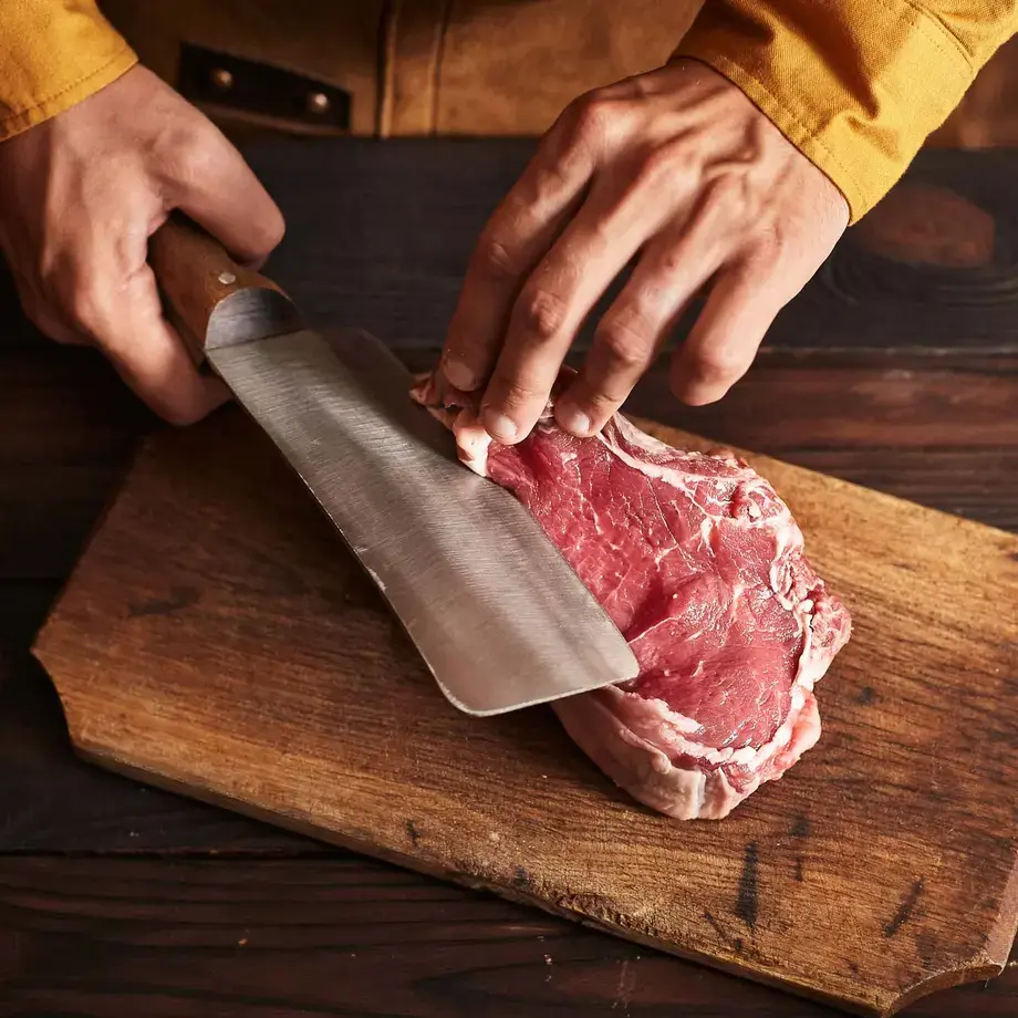 A butcher cutting a slab of lamb with a butcher's knife