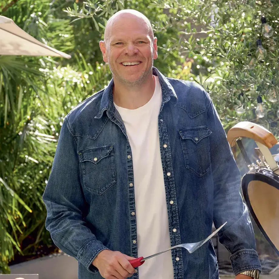 Chef Tom Kerridge standing next to a barbecue.